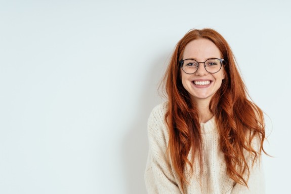junge Frau mit Brille und langen roten Haaren